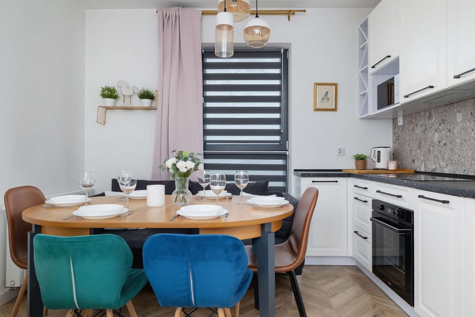 A view of the modern white kitchen and table with crockery, cups and decoration.