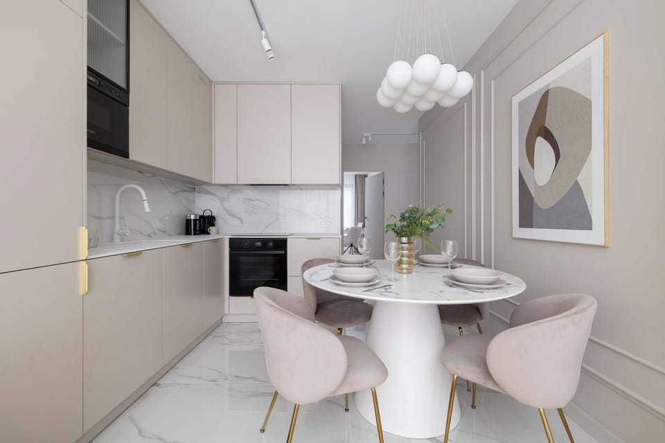 A contemporary dining space with a round marble table surrounded by stylish beige chairs and a decorative pendant light overhead.

