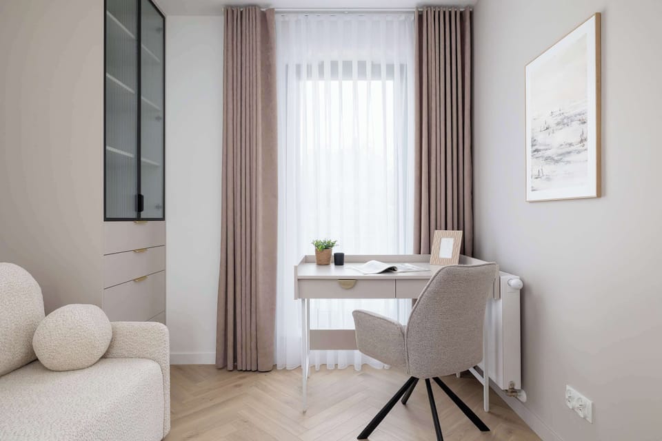 Another view of the second bedroom, this time emphasizing the writing desk placed by a large window for natural light.

