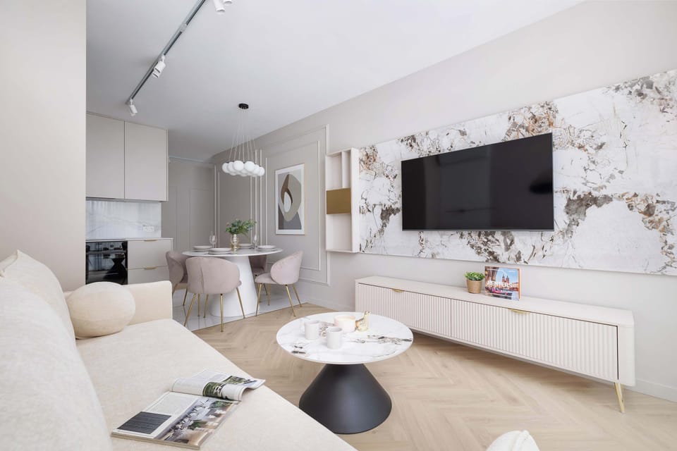 A chic and functional living room with matching light-toned furniture and a media center under a mounted TV.

