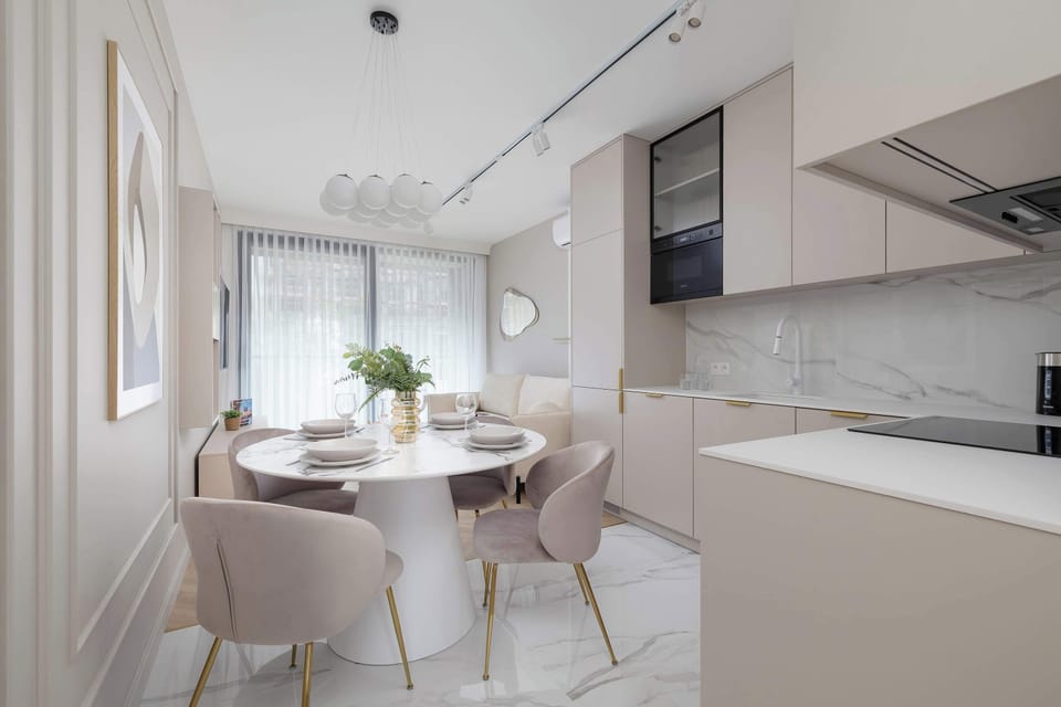 A marble-topped dining table set for four, with plush chairs and fresh flowers completing the upscale look.

