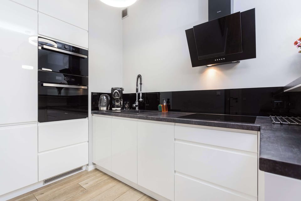 A kitchen with white cabinets, black countertops, and modern appliances. The minimalist aesthetic enhances functionality.