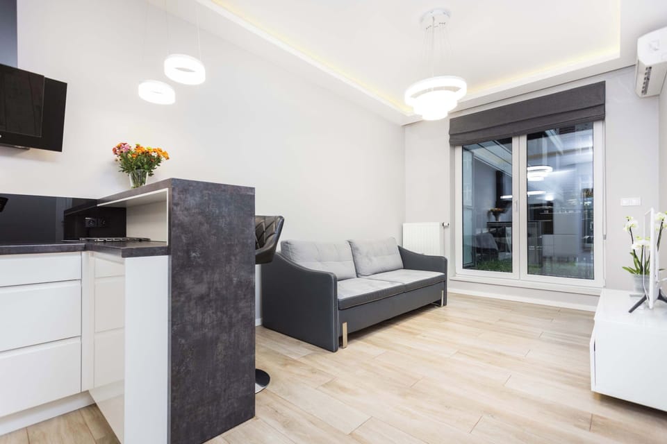 A kitchen and living room in an open-plan layout, with a black kitchen island separating the spaces. The sleek design gives a modern and elegant feel.