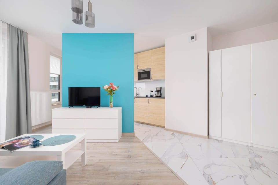 Bright and elegant living room with a white coffee table, a television, a double sofa bed, and a cabinet.
