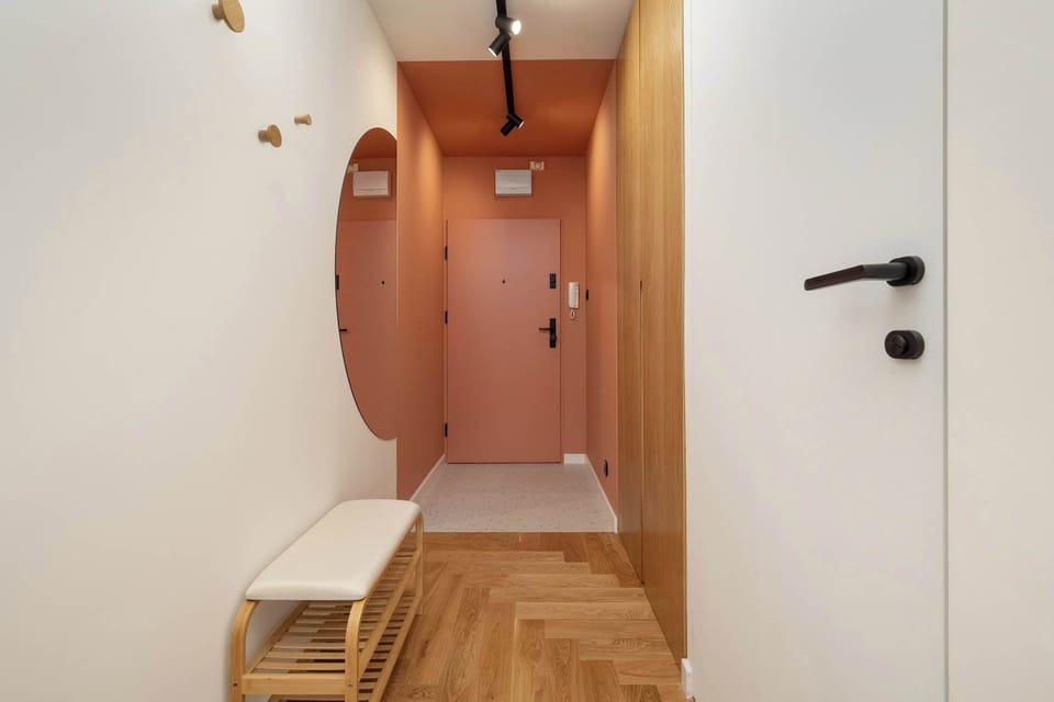 Spacious bright hallway with large round mirror and entrance to bathroom.