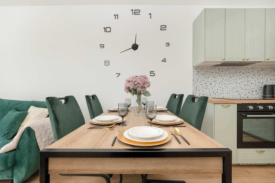 This dining area features a wooden table with green chairs. The table is set, creating a warm, inviting atmosphere.