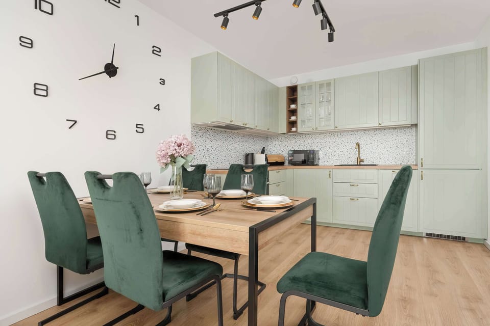 This shot shows the kitchen cabinets, wooden countertop, and dining table with settings, all in a cohesive color palette.

