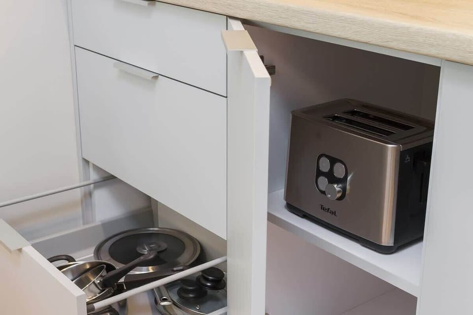 A detailed view of the kitchenette with a small stovetop, microwave, and sink. The modern design maximizes functionality in a compact area.