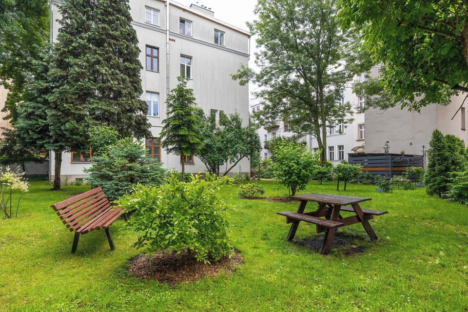 A lush green courtyard with picnic benches and trees — a peaceful spot for outdoor relaxation.