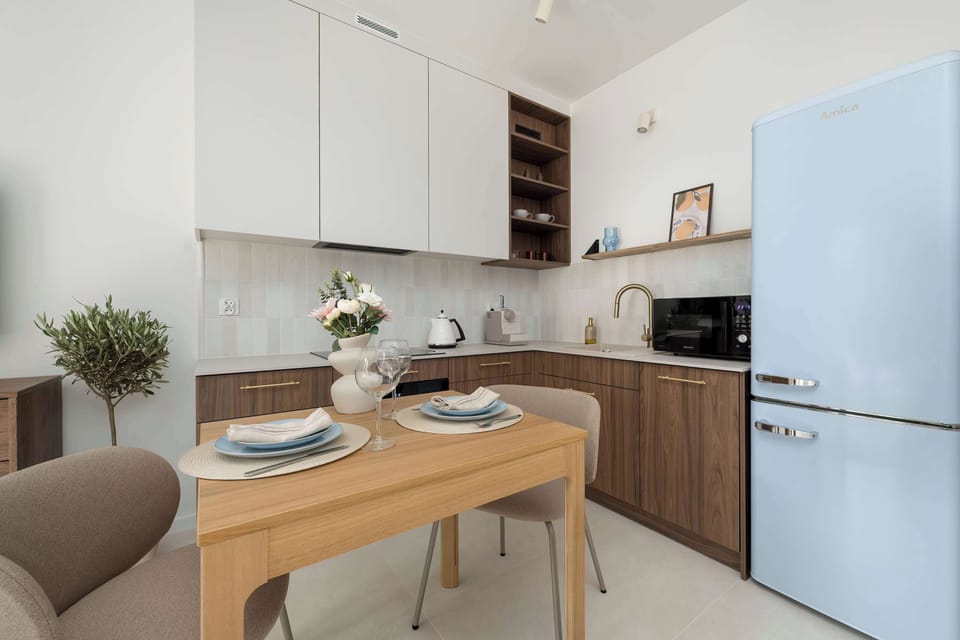 Dining area with a wooden table, two chairs, and a view of the kitchenette.