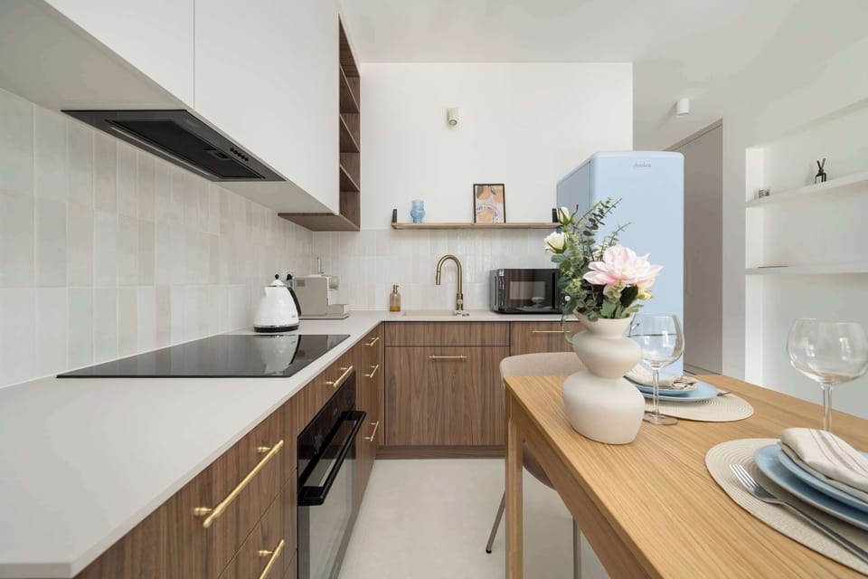 Dining area with a wooden table, two chairs, and a view of the kitchenette.