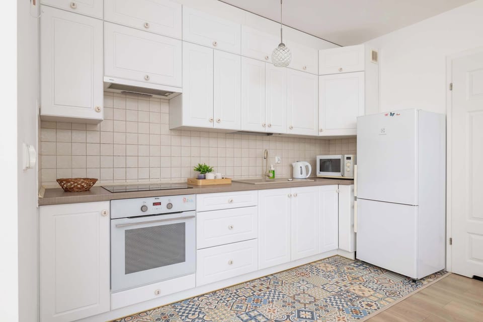 Fully equipped kitchenette with white modern cabinets.
