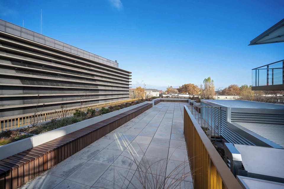 The viewing terrace offers a spacious space with modern finishes, surrounded by elegant railings and vegetation, and its location provides panoramic views of the surrounding buildings and natural landscapes, creating an ideal place to relax.