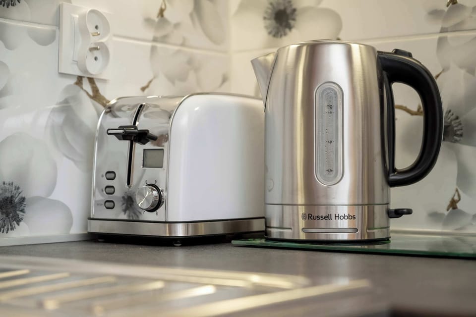 The kitchenette is equipped with modern appliances, such as a toaster and electric kettle, which harmonize with the rest of the interior, providing comfort and functionality.