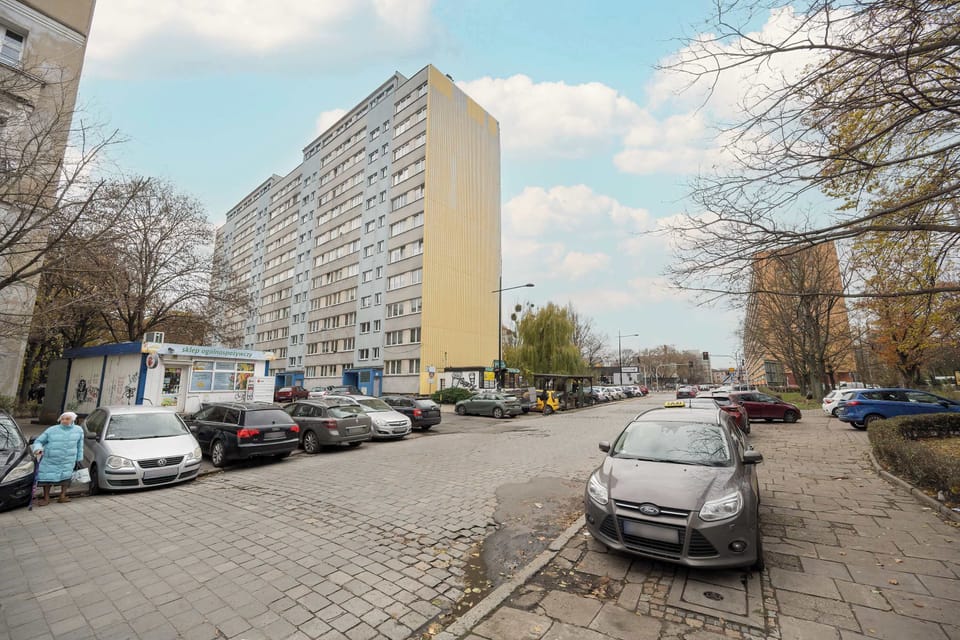 A street-level view showing parked cars and a residential building with a classic design.