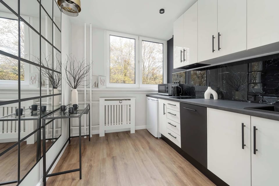 A functional kitchen featuring white cabinetry, a black countertop, and a window providing natural light.