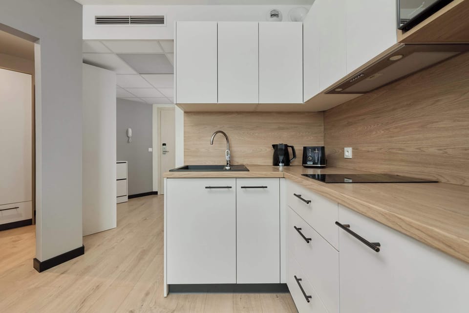 A sleek, modern kitchen with white cabinets, wooden countertops, and fully equipped with appliances.

