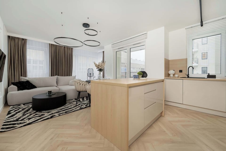 A kitchen island with bar stools, designed for casual dining or work. The surrounding kitchen is sleek and modern.