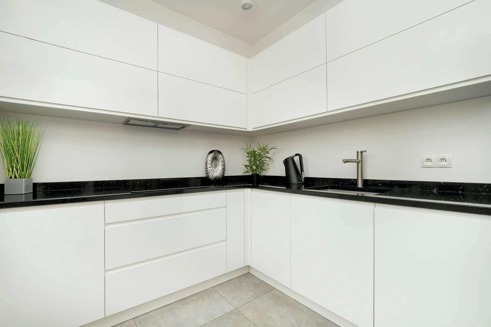 Another shot of the modern kitchen, with a view of the L-shaped countertop, white cabinets, and black accents.