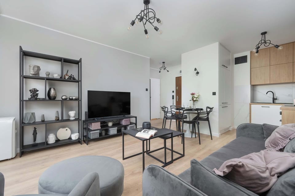 A well-lit dining and living area with gray seating, round tables, and decorative wall art.