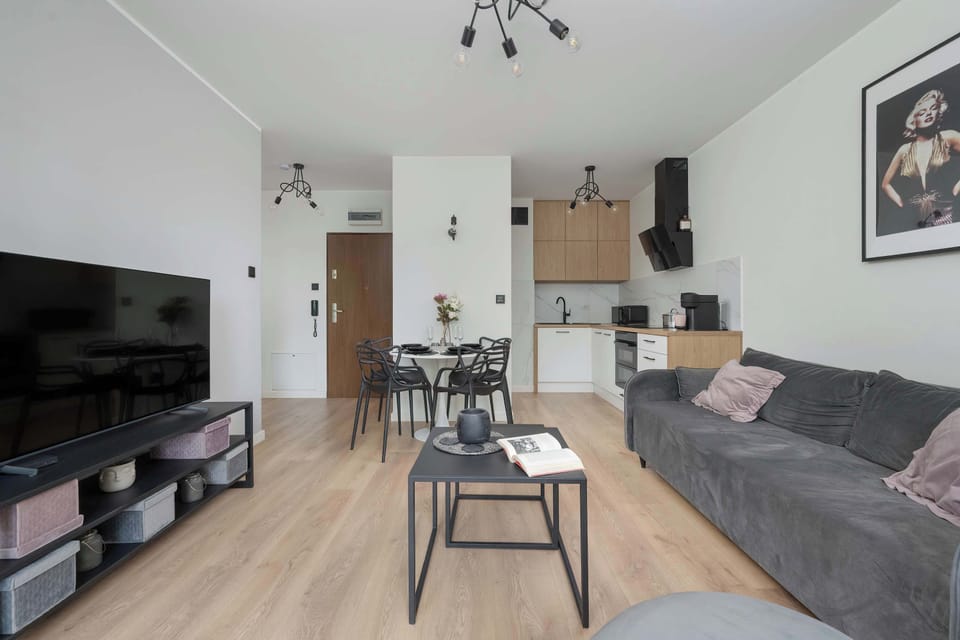 A dining area connected to the kitchen with black chairs, a round table, and modern black-and-white decor.