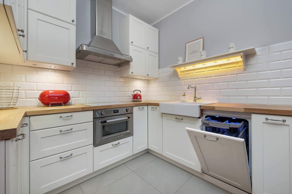 A bright kitchen with a spacious countertop, dishwasher, and modern range hood ensures comfort while preparing meals.