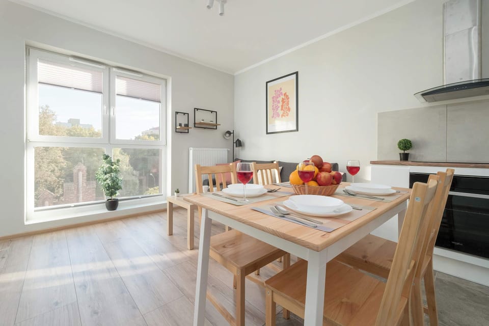 This angle shows more of the living area and the dining table. Large windows let in a lot of natural light, creating a pleasant, airy atmosphere.