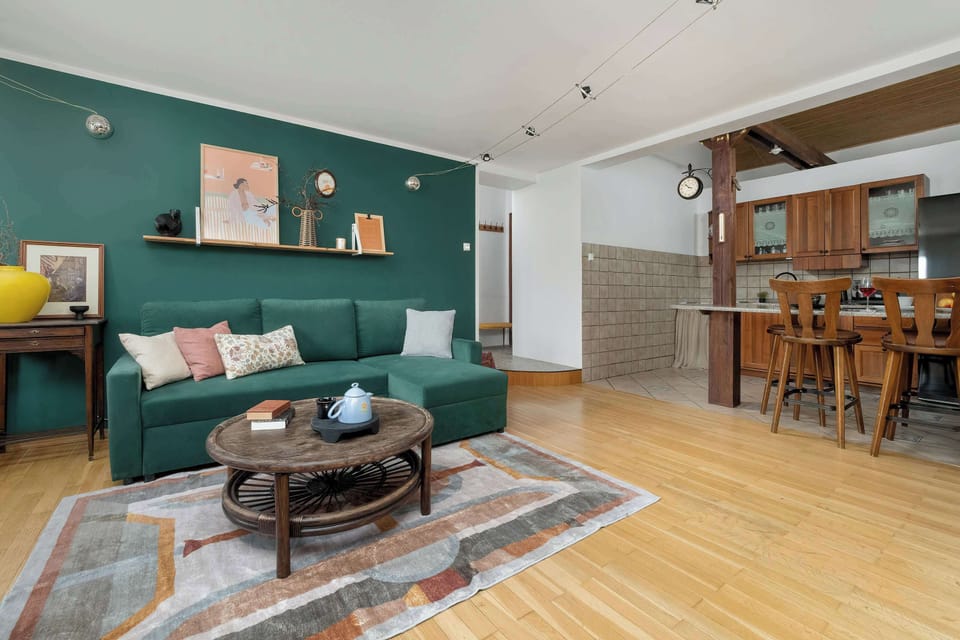 Living room with a green corner sofa, TV, coffee table, and a cozy, stylish vibe.