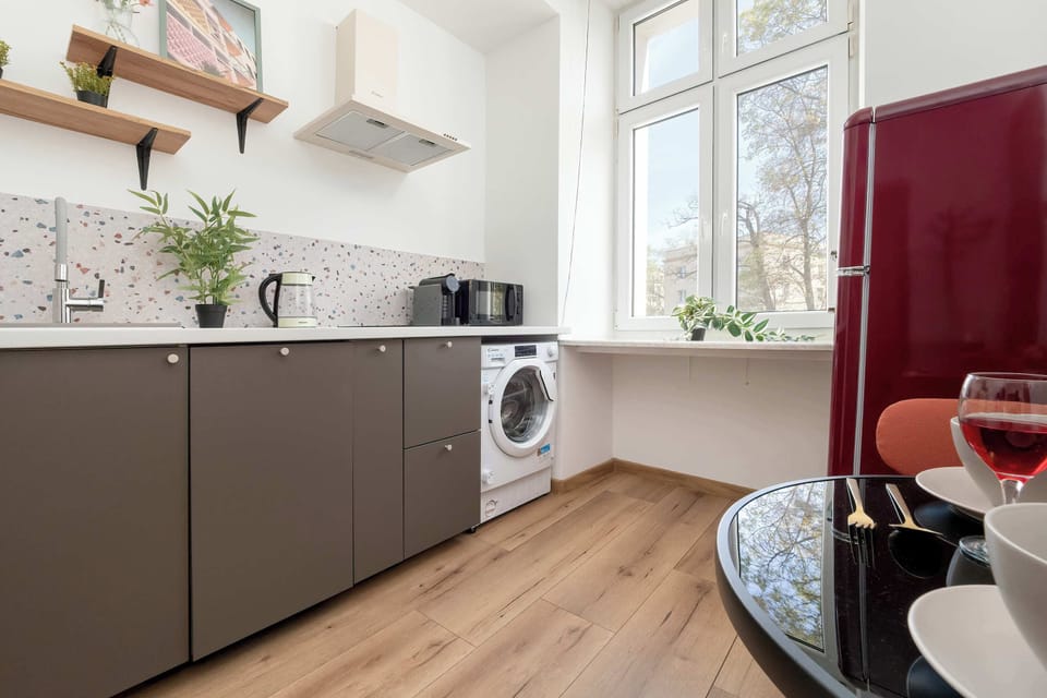 The kitchen with a red fridge and a round table by the window invites cozy shared meals.