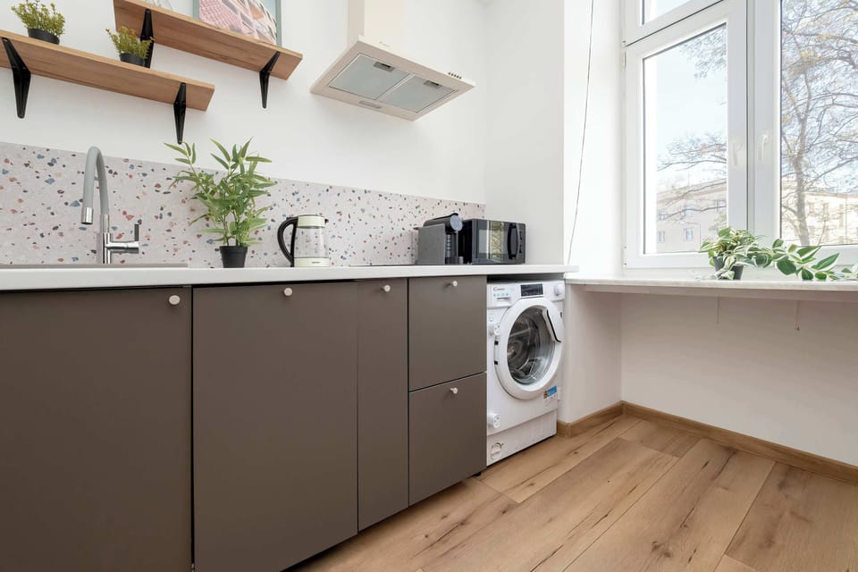 A functional kitchen with modern cabinets and a washing machine makes longer stays more convenient.