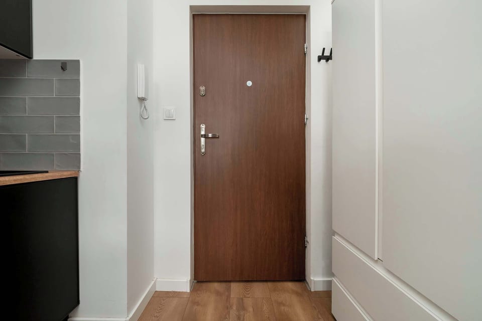 A direct view of the entrance to the studio, featuring a wooden door and white interior walls.
