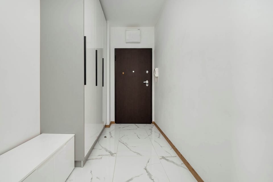 Modern hallway with secure entry door and white tile flooring – Bright and welcoming entrance with a clean aesthetic.