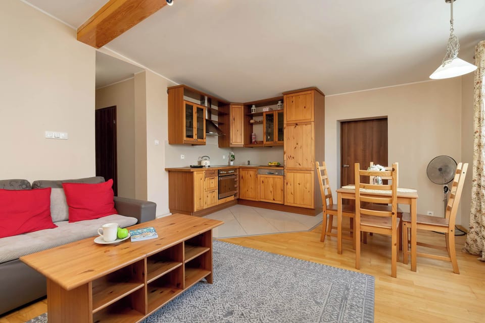 A bright and inviting living room seamlessly connected to a fully equipped wooden kitchenette, perfect for relaxing and cooking in one open space.
