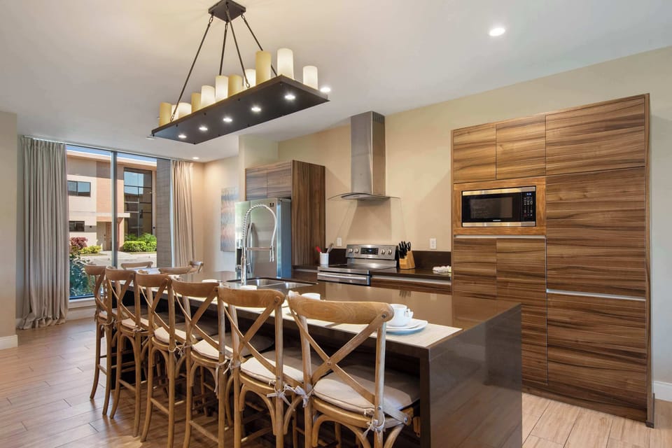 Elegant kitchen with wood cabinetry, spacious island seating, and bright patio access.
