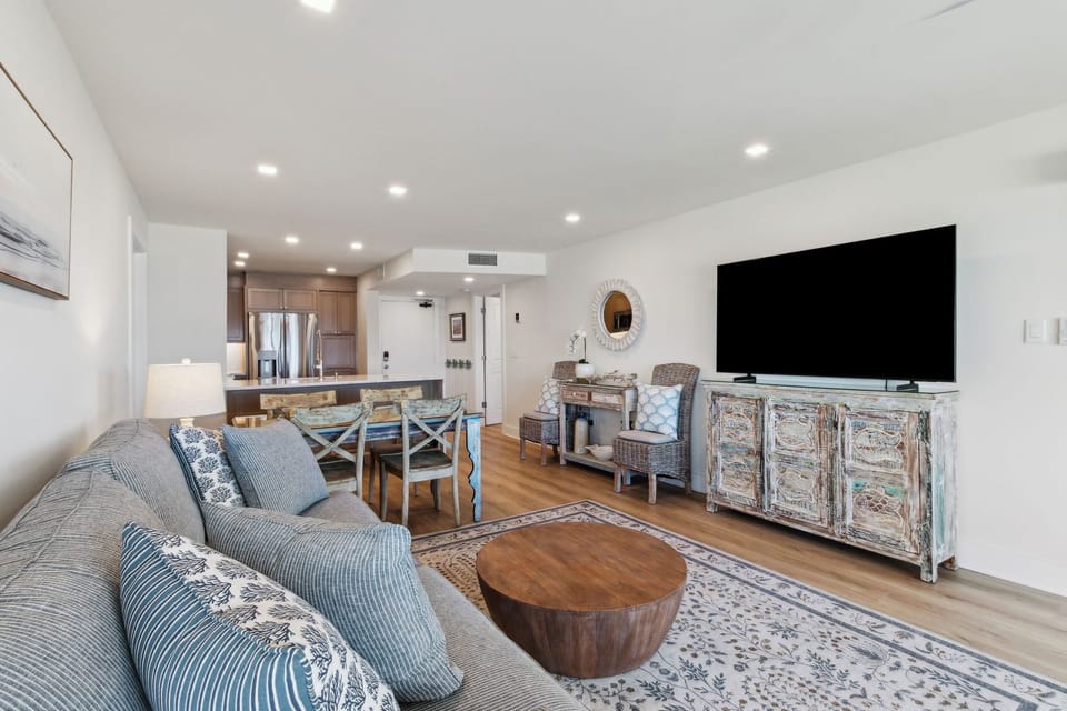 Relaxing Living Area Featuring Plush Couch and Chairs, Flat Screen Smart TV, and Modern Coastal Decor