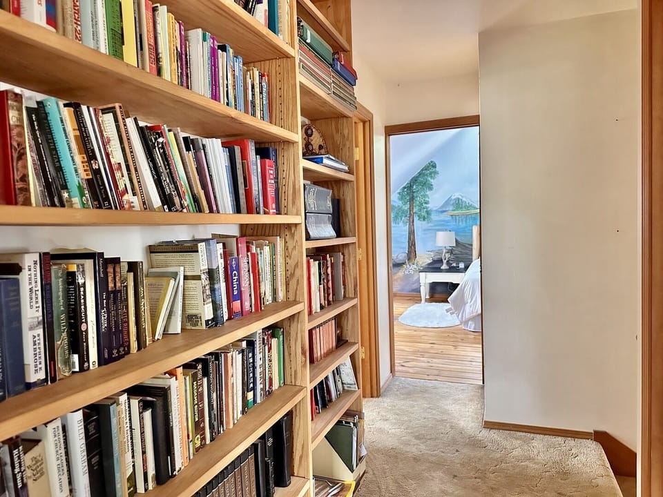 Your personal reading sanctuary awaits, with floor-to-ceiling shelves brimming with stories and a peaceful bedroom beyond.