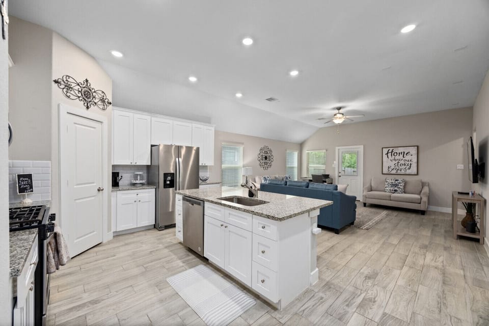 Bright open-concept kitchen and living area with granite island, stainless steel appliances, and easy flow for groups
