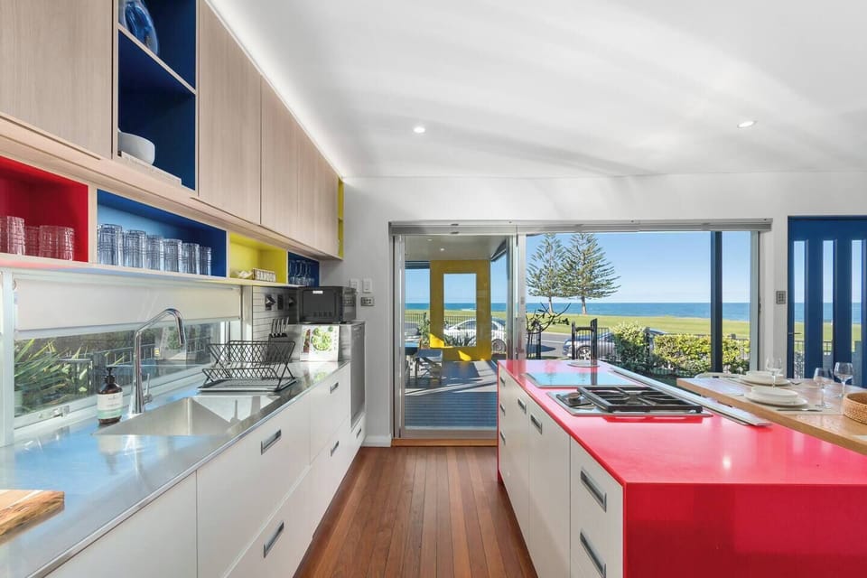 Whip up meals in the colourful kitchen, complete with a striking red island, modern appliances, and easy access to the patio for breezy breakfasts or sunset drinks.