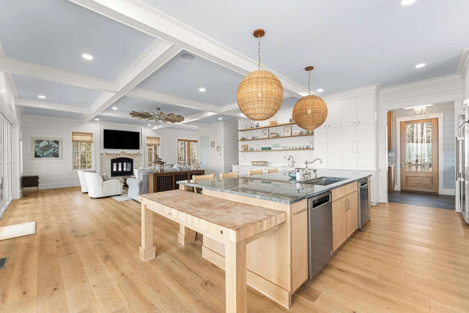 The chef’s kitchen is as striking as it is functional, anchored by a dramatic waterfall island and artisan butcher block. Overhead, woven pendants warm the space, while open shelving adds charm and character. 