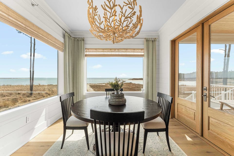 Dine with a front-row seat to the bay. This intimate round dining space is wrapped in windows, framed by breezy drapes, and crowned with a sculptural coral-inspired chandelier. It's the ideal setting for slow breakfasts or evening wine with a view.