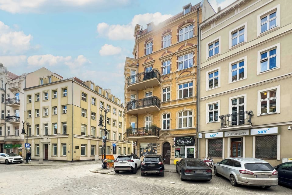 A wider street scene capturing historic buildings with ornate facades and parked cars, portraying the vibrant urban surroundings.