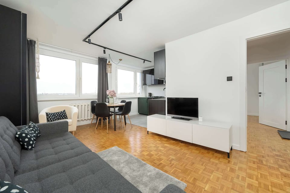 Functional and comfortable living room with television, kitchenette, dining area, double sofa bed, and armchair.