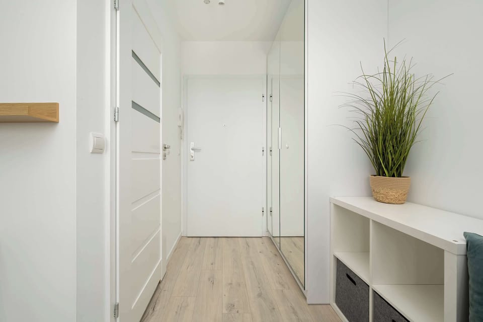 Bright hallway with white shelves and white doors.