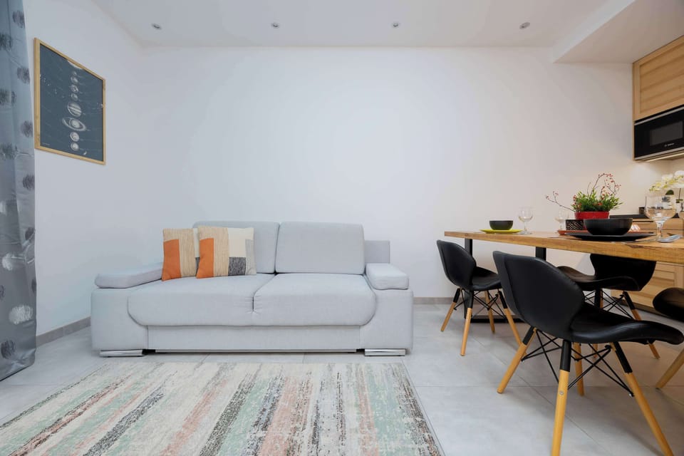 A closer look at the living room, highlighting a sectional sofa with pillows and a TV mounted on the wall.