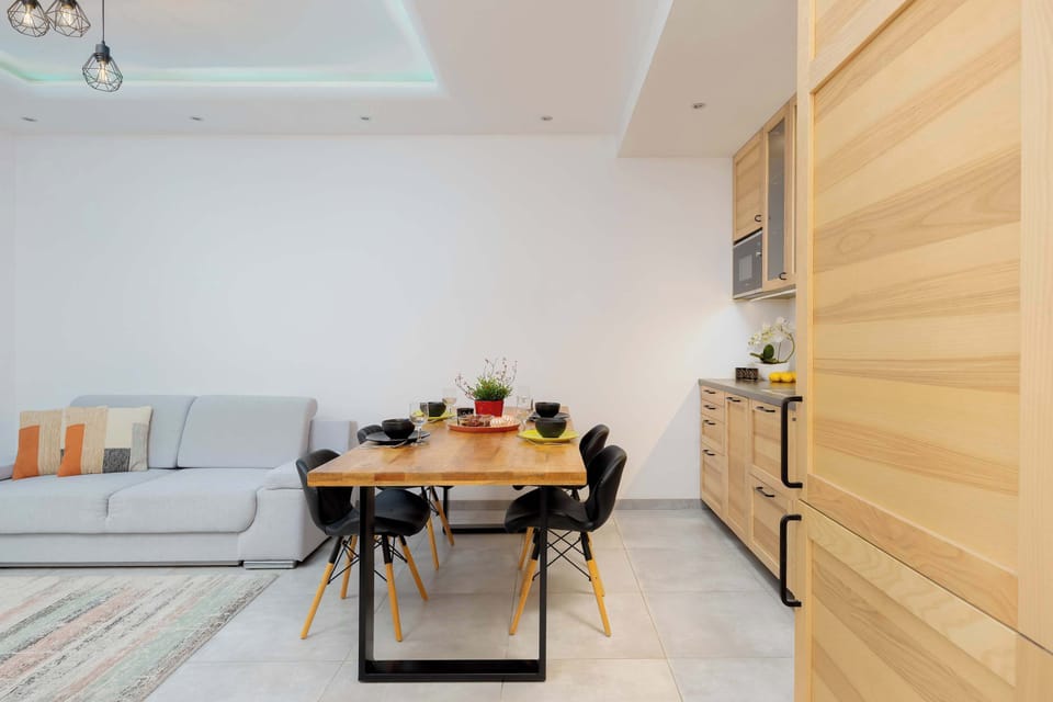 The living room features a comfortable sofa and a wooden dining table set with chairs. It’s a cozy space, perfect for both relaxation and dining.