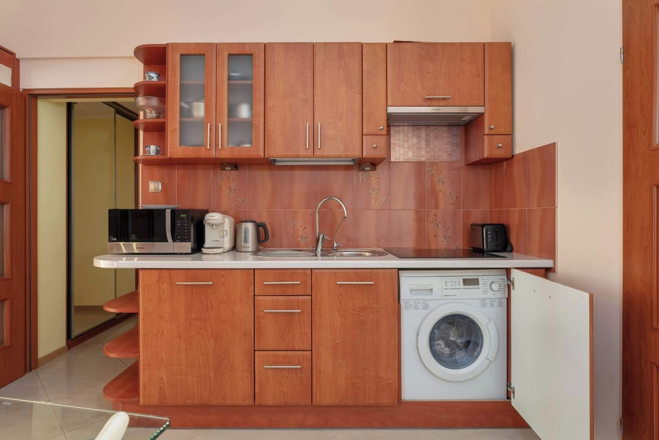 Another angle of the kitchen area, showing the washing machine, sink, and additional countertop space.

