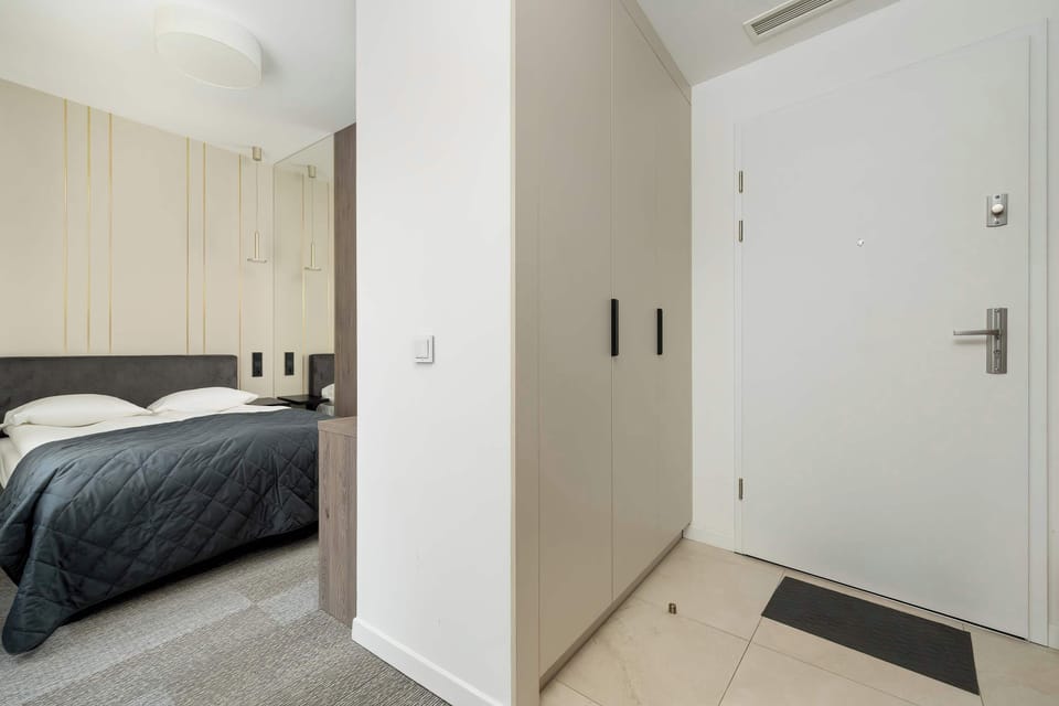 A partial view of the bedroom leading into the hallway, showing the white doors and sleek built-in wardrobe.

