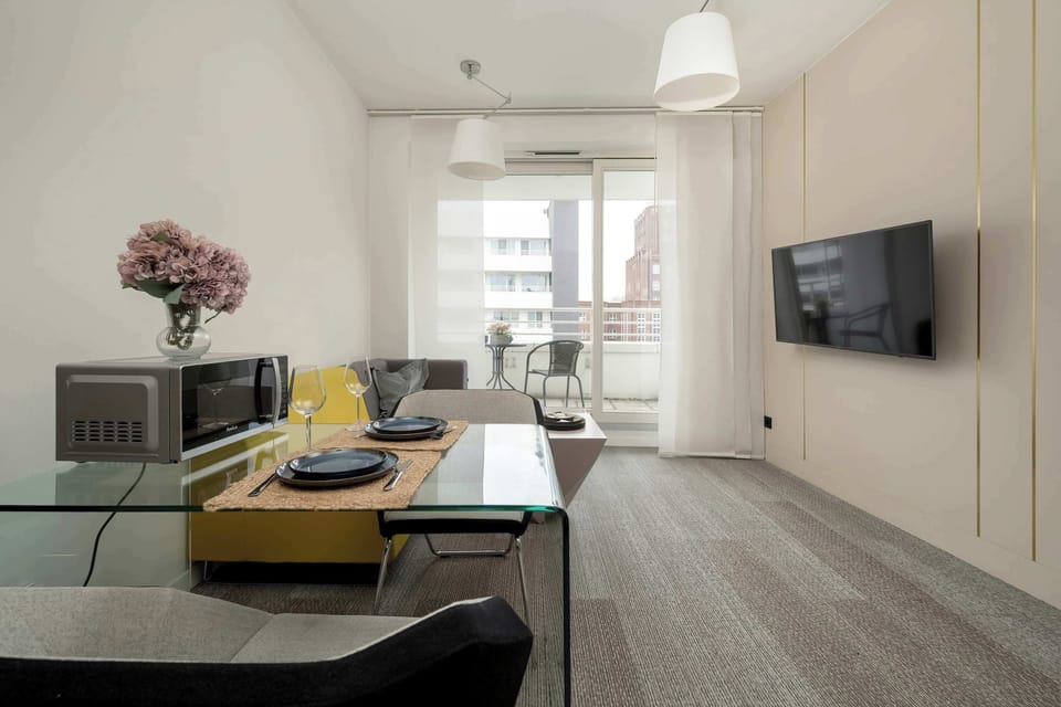A modern living room blending into the kitchen space, with wood accents and a yellow-and-grey color theme.