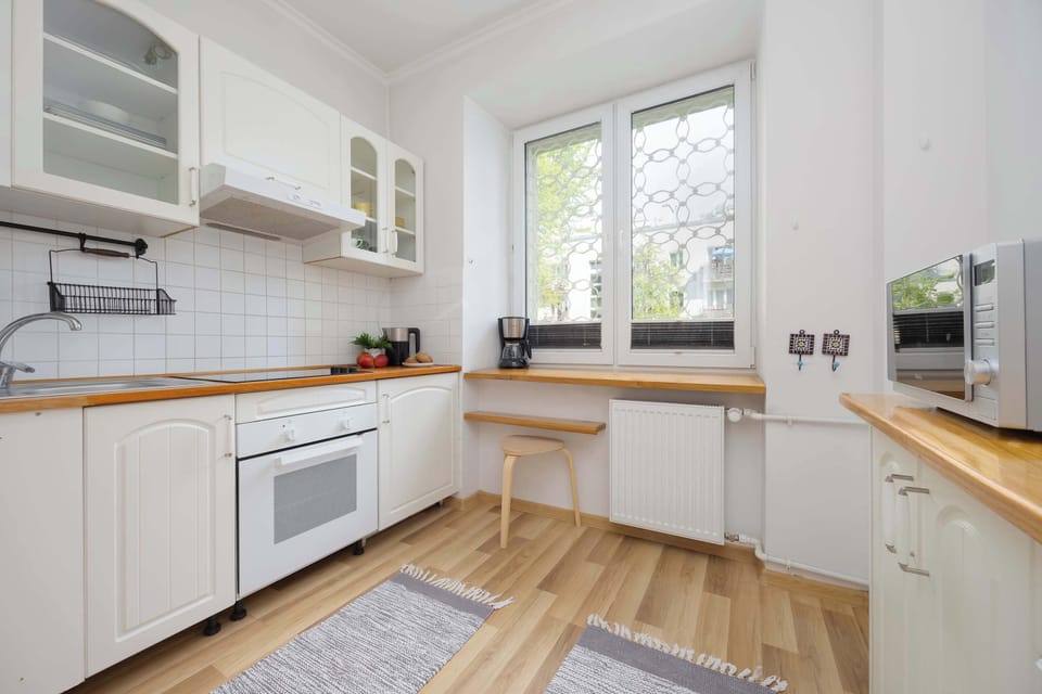 Fully equipped kitchen with with light-colored cabinets and a wooden countertop.