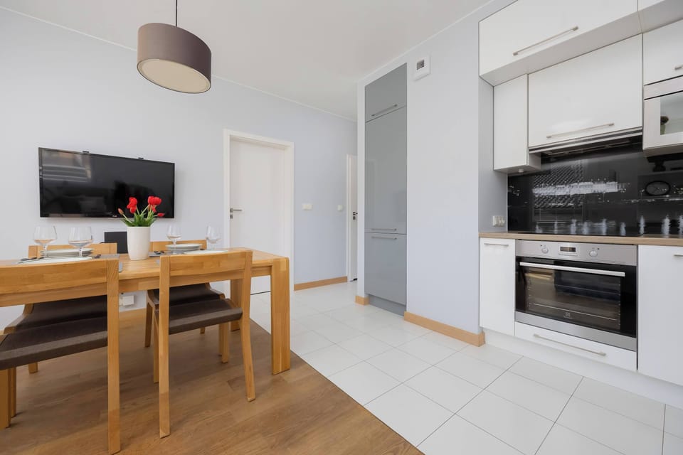 A well-equipped kitchenette with white cabinets, a built-in oven, and a black backsplash.
